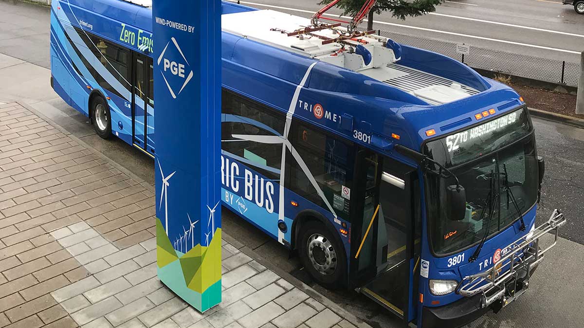 TriMet New Flyer electric bus parked at charging station.