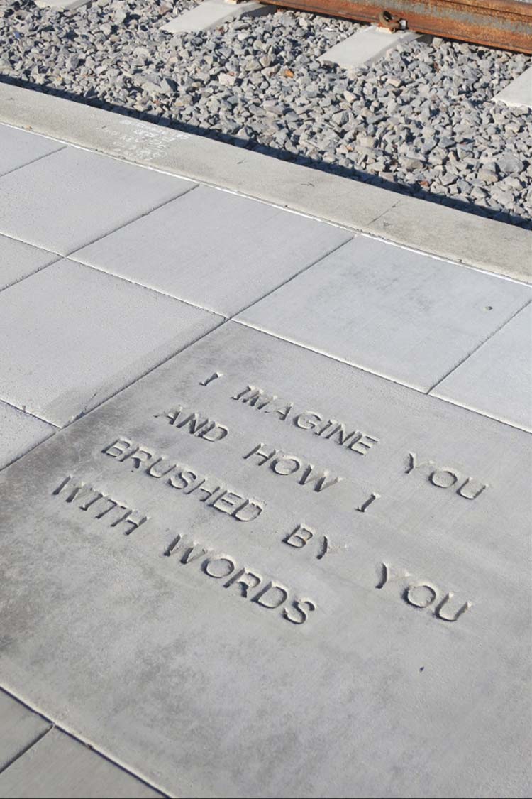Phrases stamped into new concrete on the site include 'I imagine you and how I brushed by you with words'