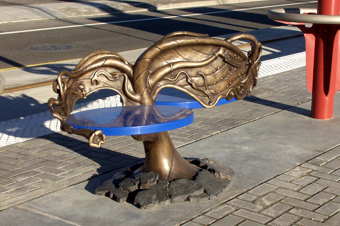 Small metal bench sculpture with blue seats