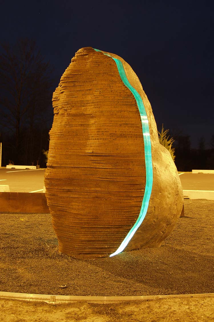 Monolith - huge stone sculpture with a band of bright green lighting on one side