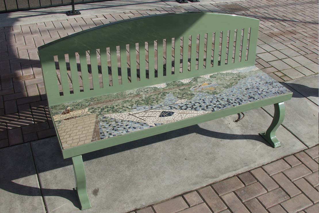 A green metal and tile mosiac bench