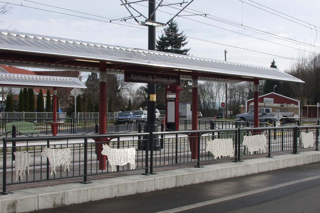 Metal cows on the dividing railing between the street and light rail platform